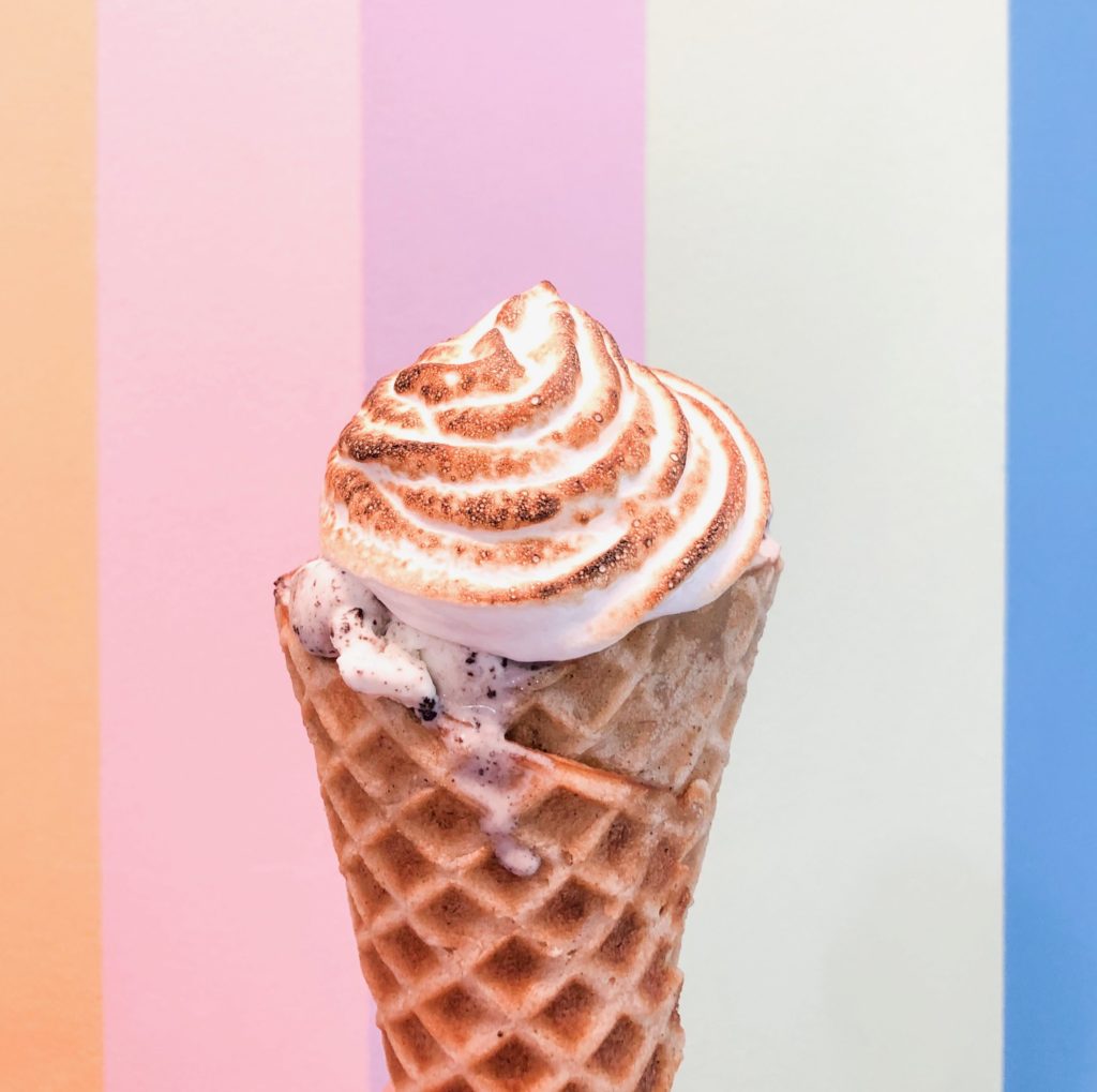 torched marshmallow ice cream waffle cone with rainbow stripe background at Wild Scoops in Anchorage alaska