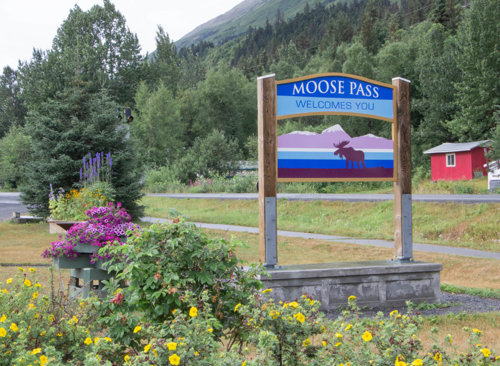 Moose Pass sign in alaska with flowers and trees