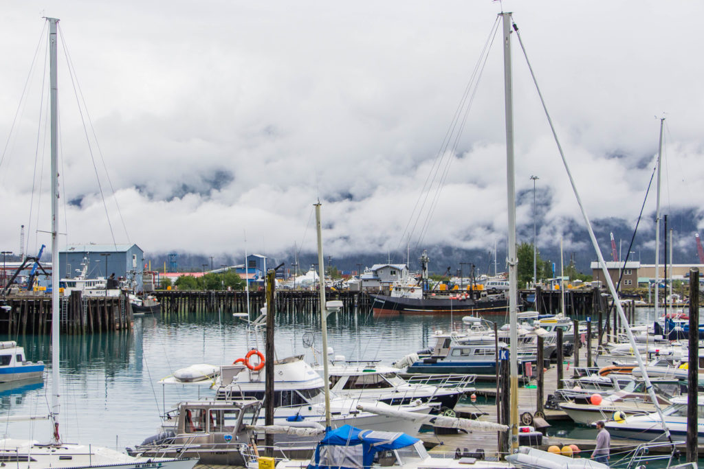 Seward Harbor and foggy cloudy mountains in Alaska with many white boats
