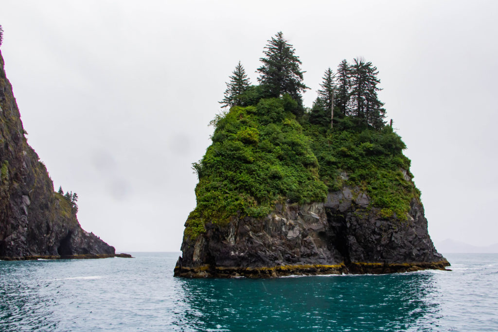 Spire Cove rocky islands and trees in the blue ocean water in Seward alaska
