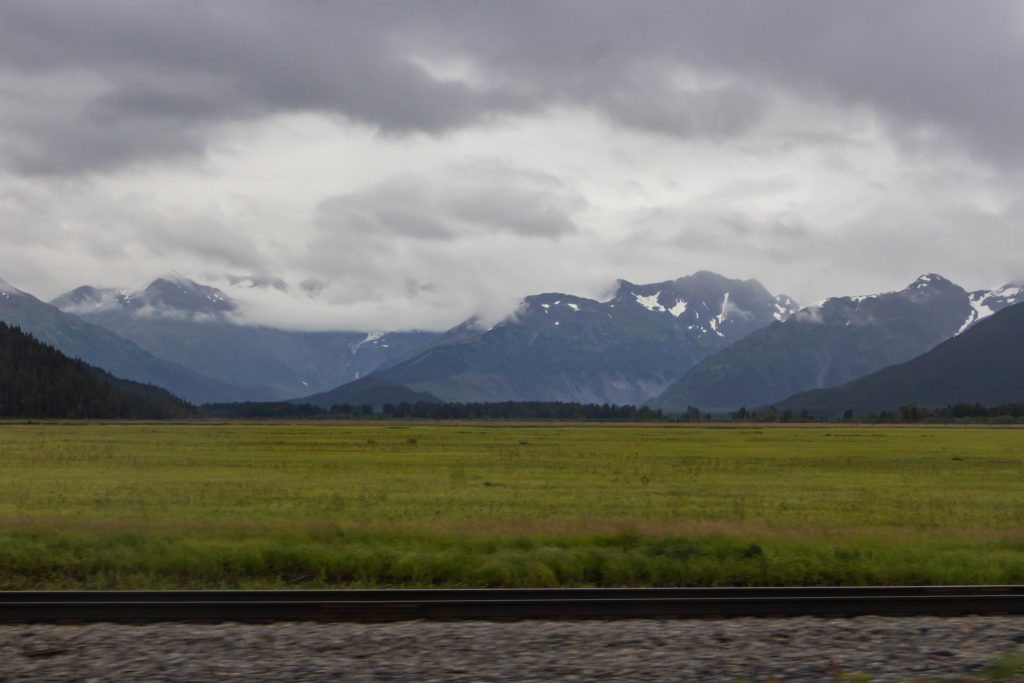 snowy mountains on cloudy day with green grass on Seward Highway, Alaska