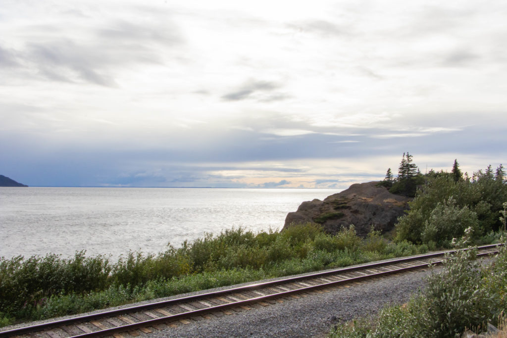 alaskan railroad tracks beside water at sunset on seward highway alaska