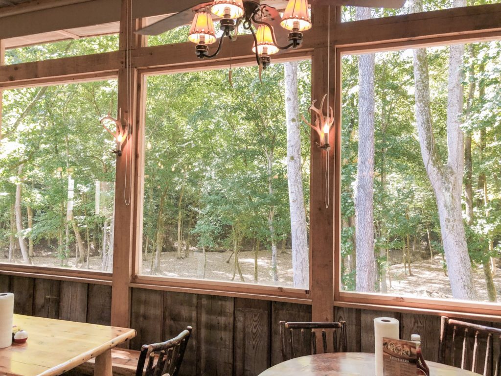 window view of woods, rustic interior design with chairs, tables, and chandelier at outpost pickwick tennessee