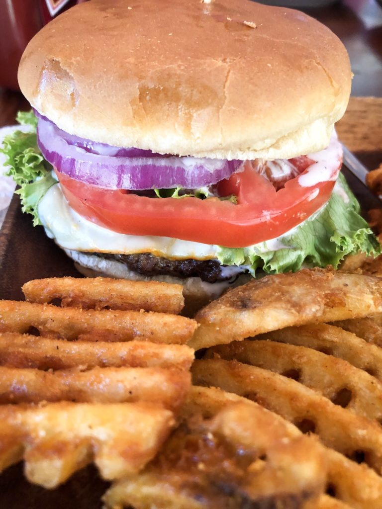 Outpost burger with lettuce, onion, tomato, and cheese and seasoned waffle fries at the outpost pickwick savannah tennessee